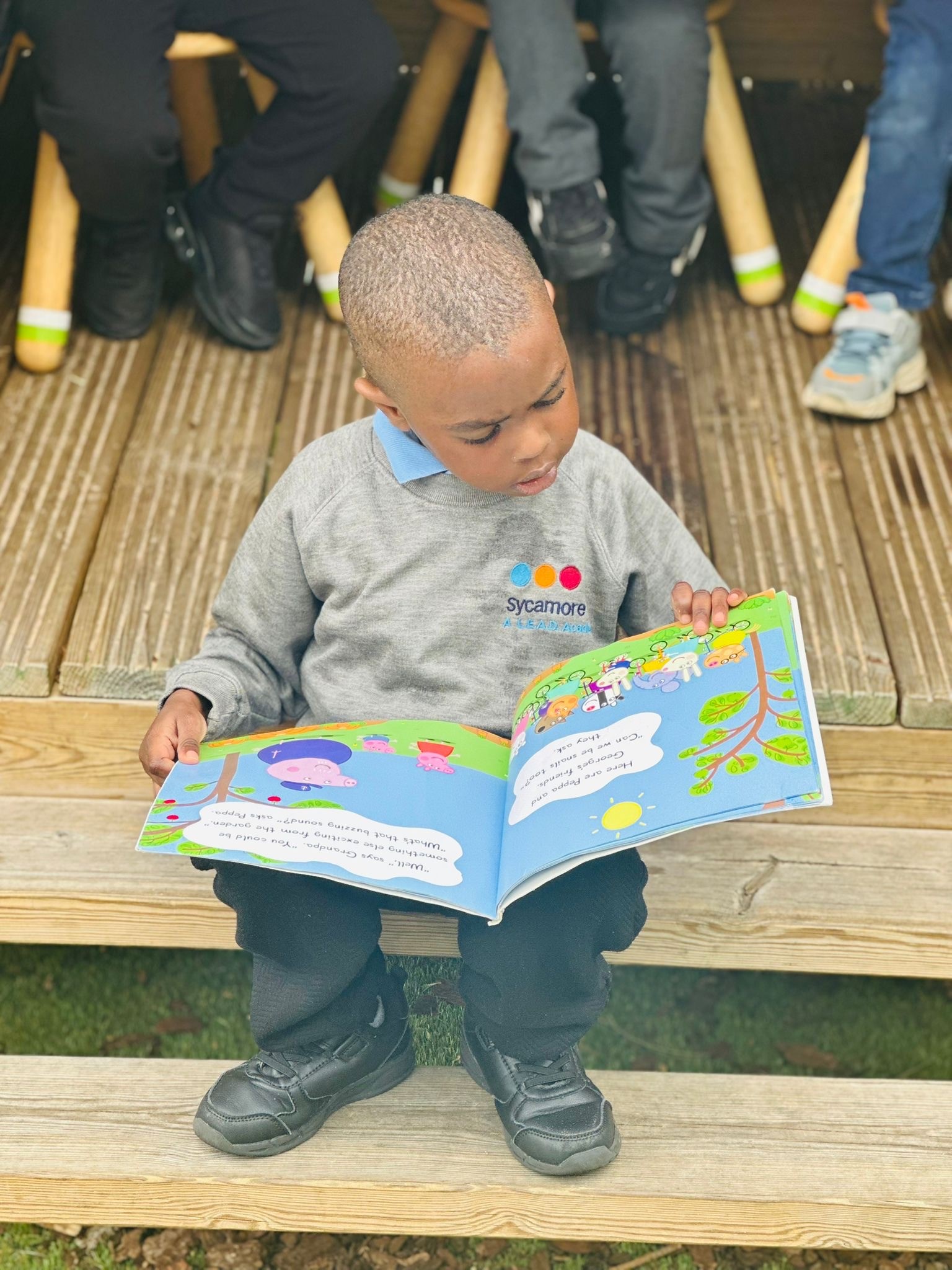 Sycamore Nursery child reading outside